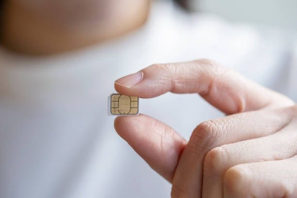 A person's hand holds a SIM card
